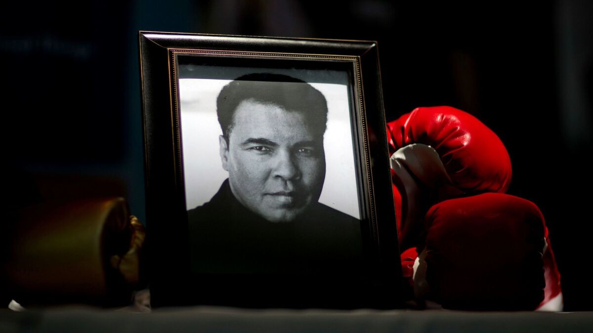 A portrait of Muhammad Ali is displayed next to a pair of boxing gloves at the "I Am Ali Festival" in Louisville.