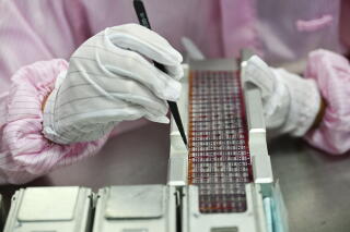 A hand with tweezers on a silicon wafer