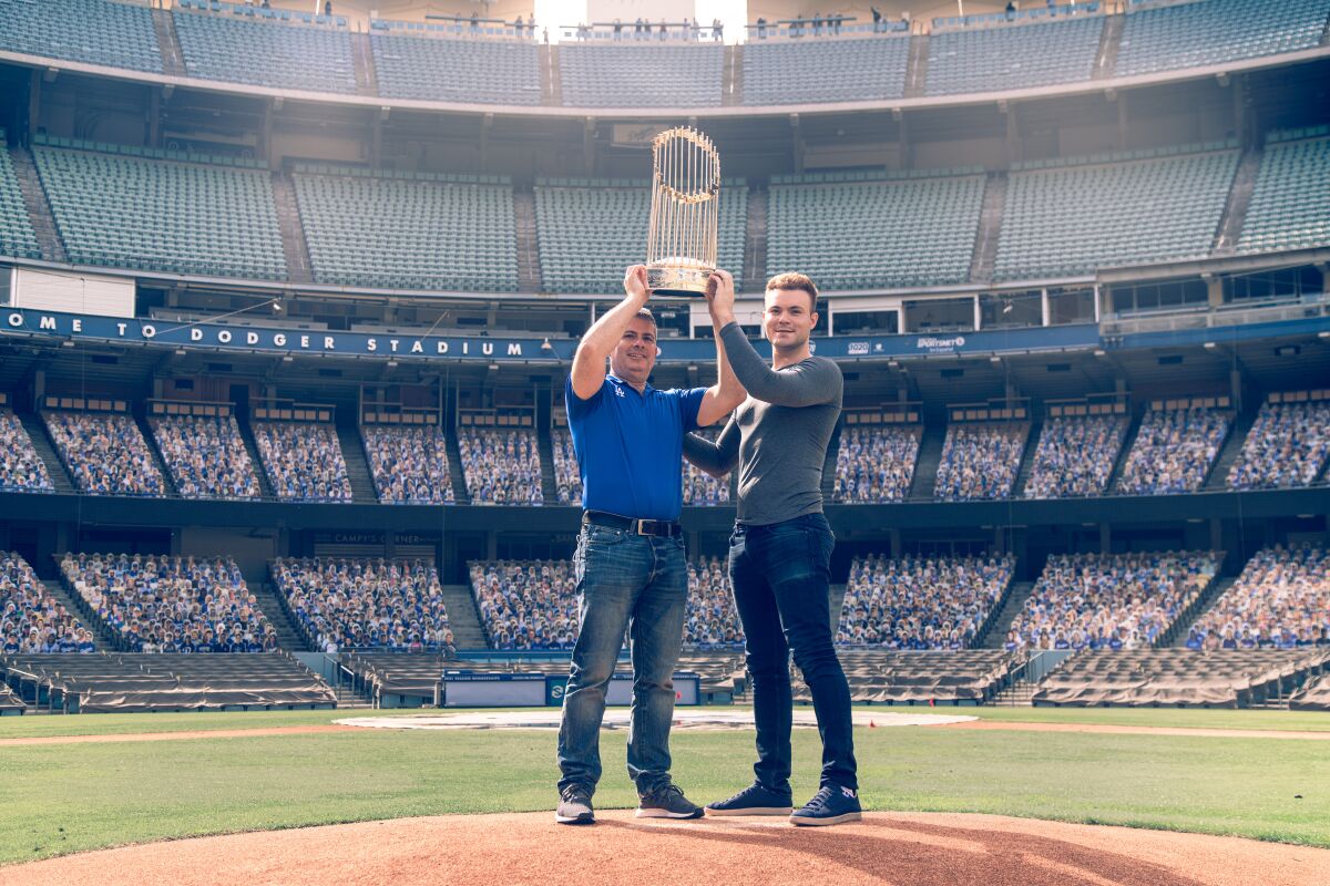 Erik Braverman, left, and Jonathan Cottrell hold the 2020 World Series trophy at Dodger Stadium.