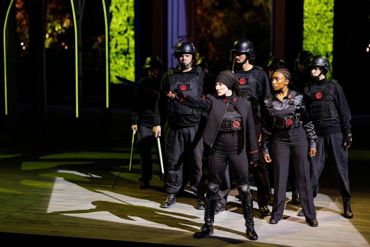 Five cast members onstage dressed in black military garb 