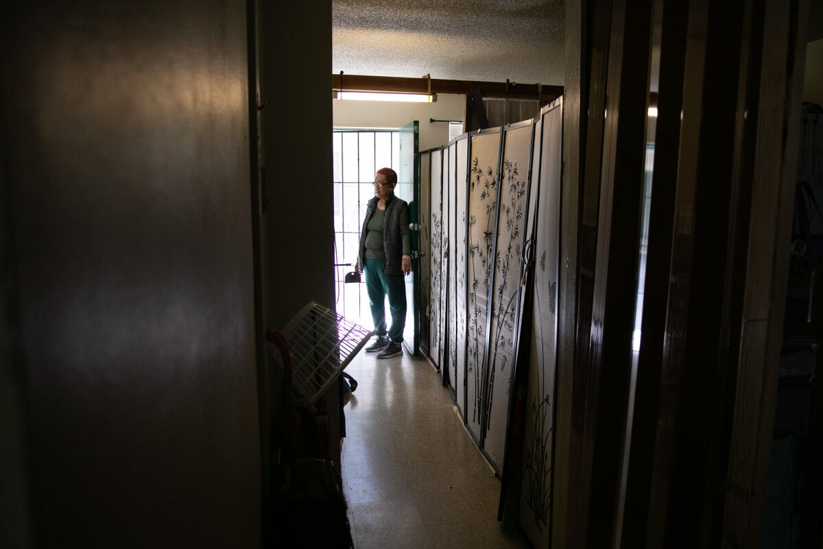 A woman stands in the entrance of a dark apartment.