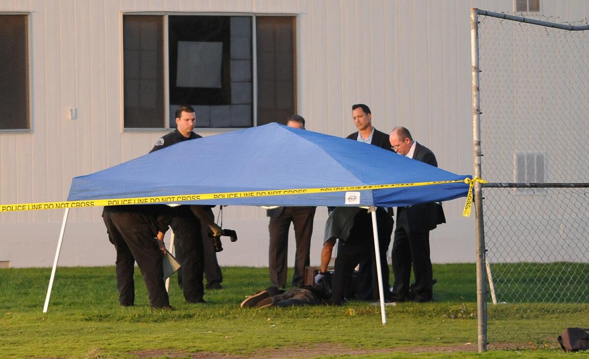 Investigators stand over a body at Mardona Middle School, where Torrance police officers had shot and killed an attempted-murder suspect.