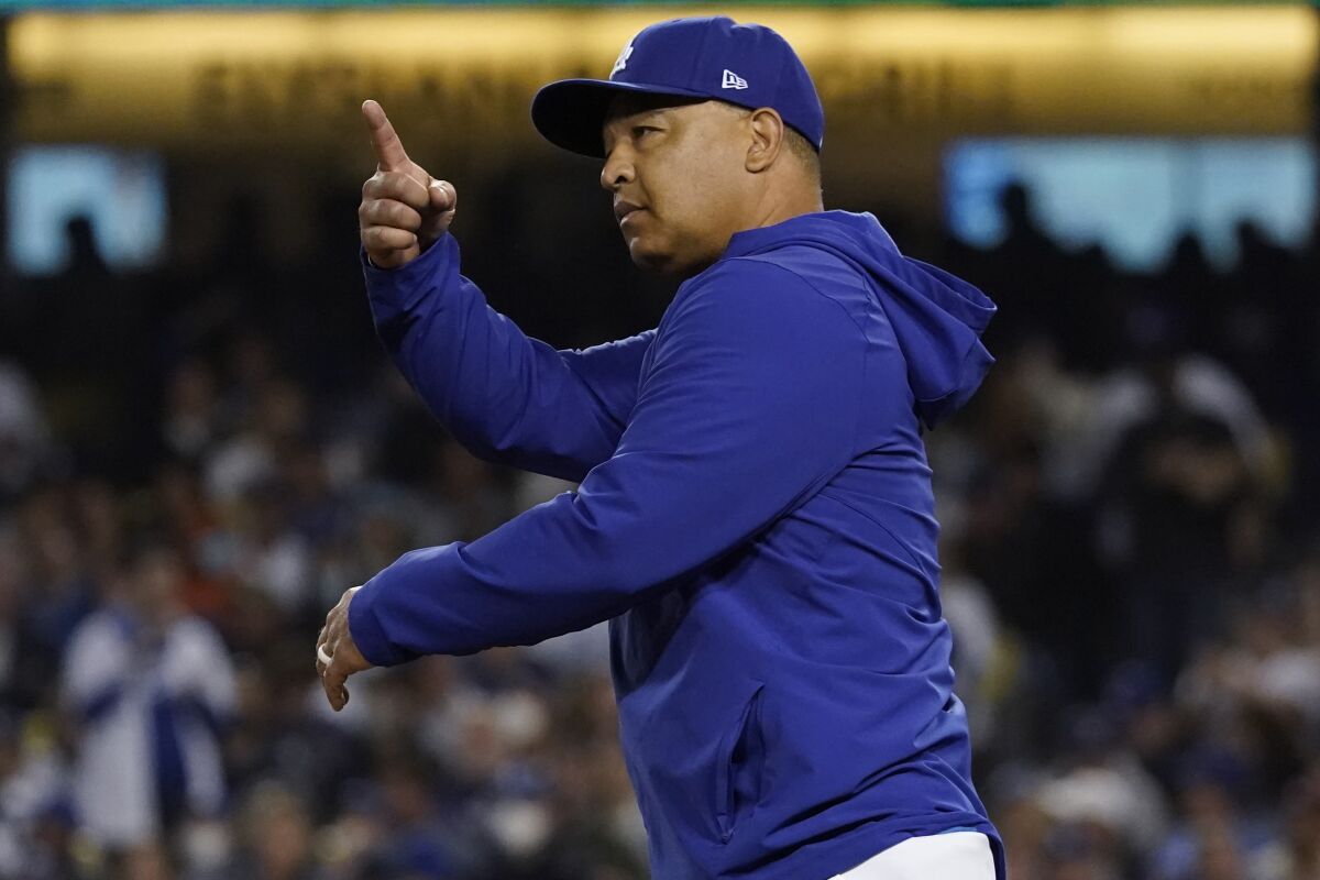 Dodgers manager Dave Roberts signals for a pitching change as he walks to the mound.