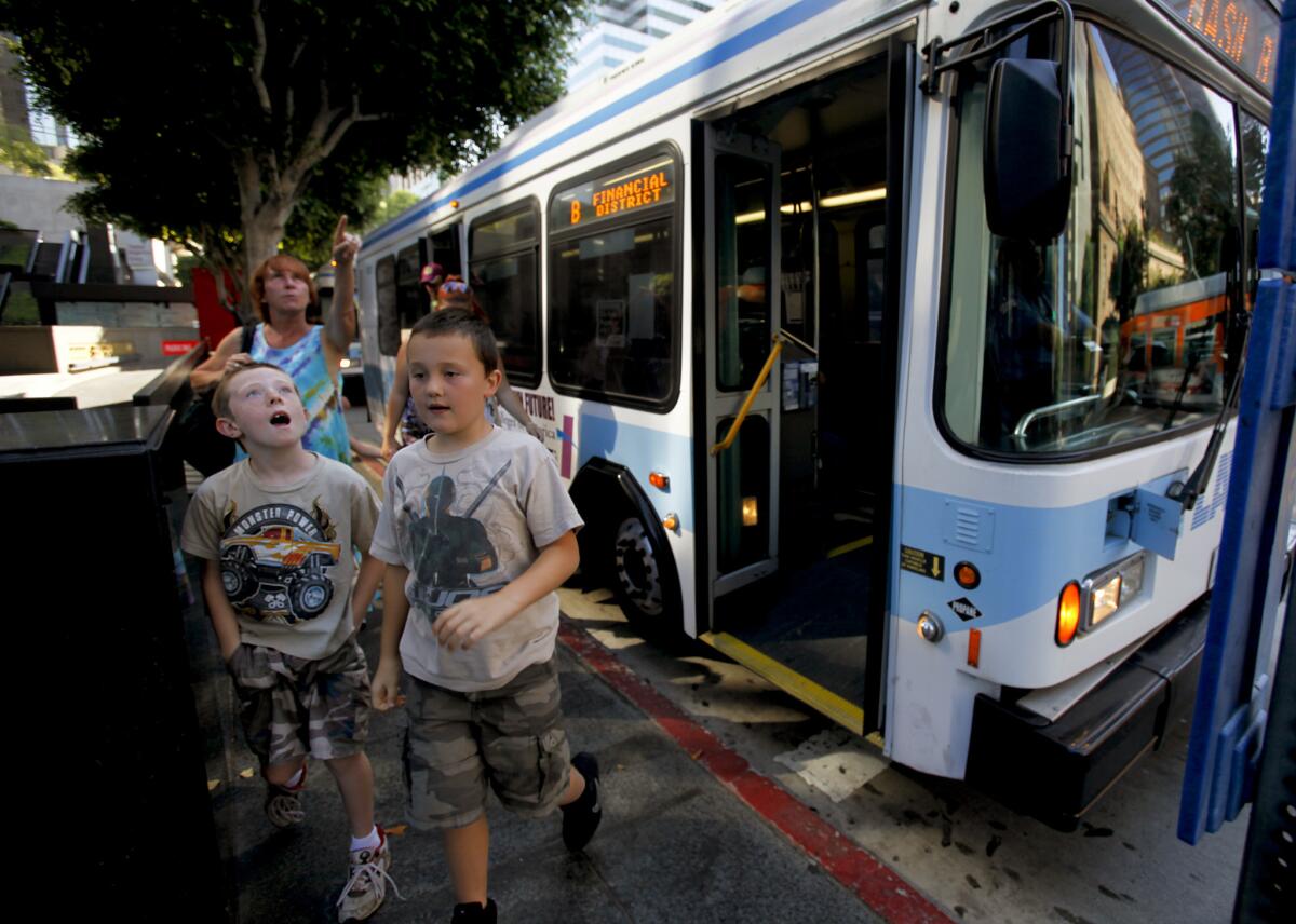 Brothers Spencer and Angel Holleman are all eyes as they depart a DASH bus in downtown Los Angeles with their grandmother Sharon behind them, in July 2011.