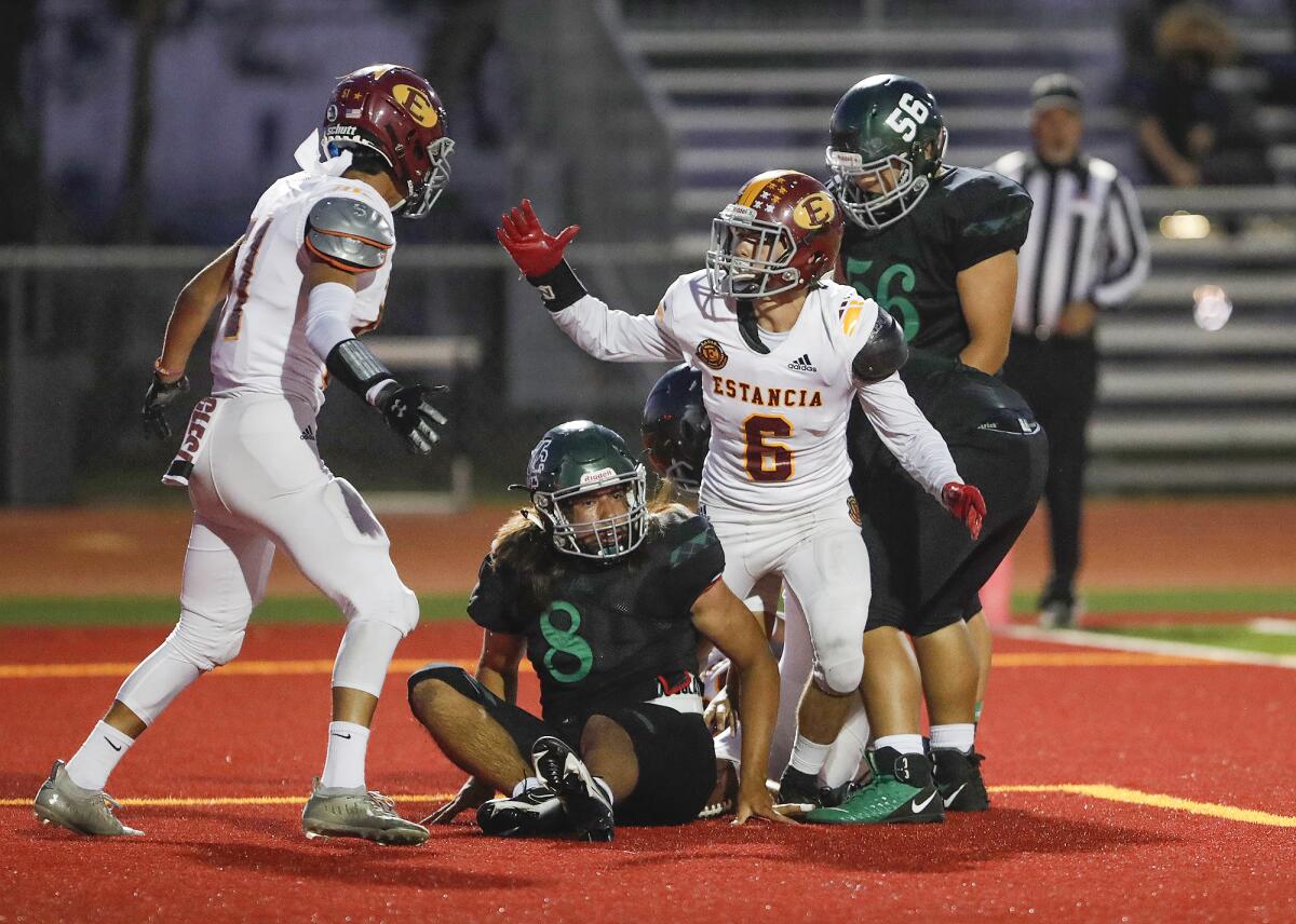 Estancia's Chris Pacheco (51) and Noah Aires (6) close in on Costa Mesa quarterback Nick Burton (8) for a sack and a safety.