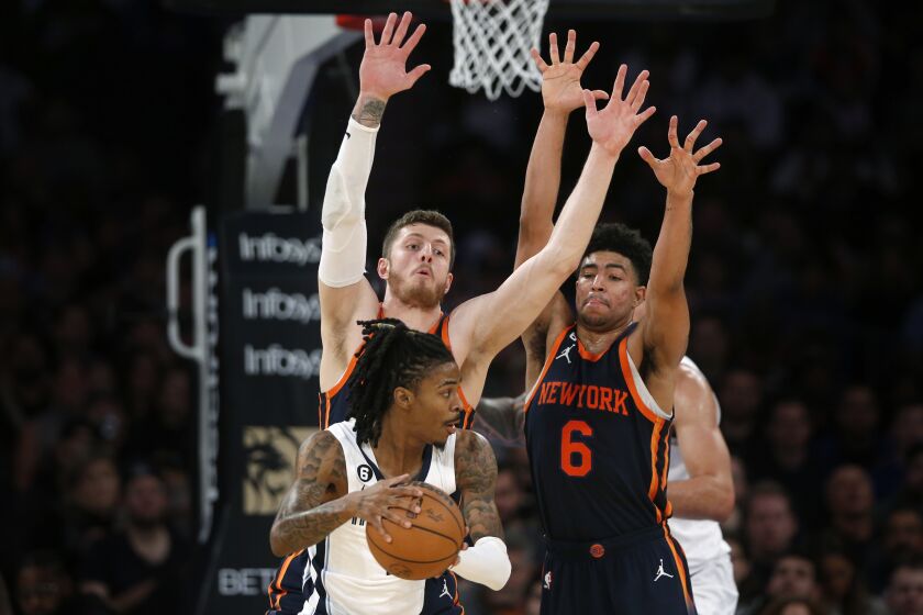 Memphis Grizzlies guard Ja Morant, with the ball, is defended by New York Knicks center Isaiah Hartenstein, left, and guard Quentin Grimes (6) during the first half of an NBA basketball game, Sunday, Nov. 27, 2022, in New York. (AP Photo/John Munson)