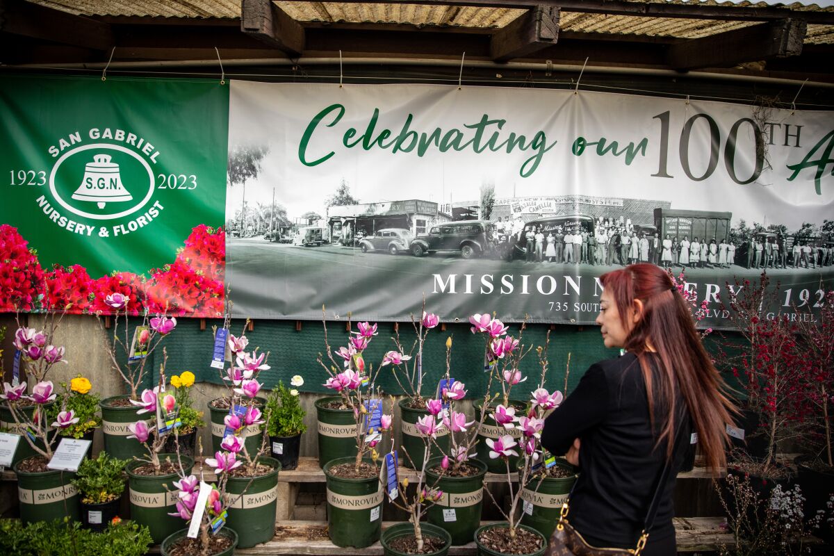 A customer in front of a banner reading "Celebrating our 100th Anniversary."