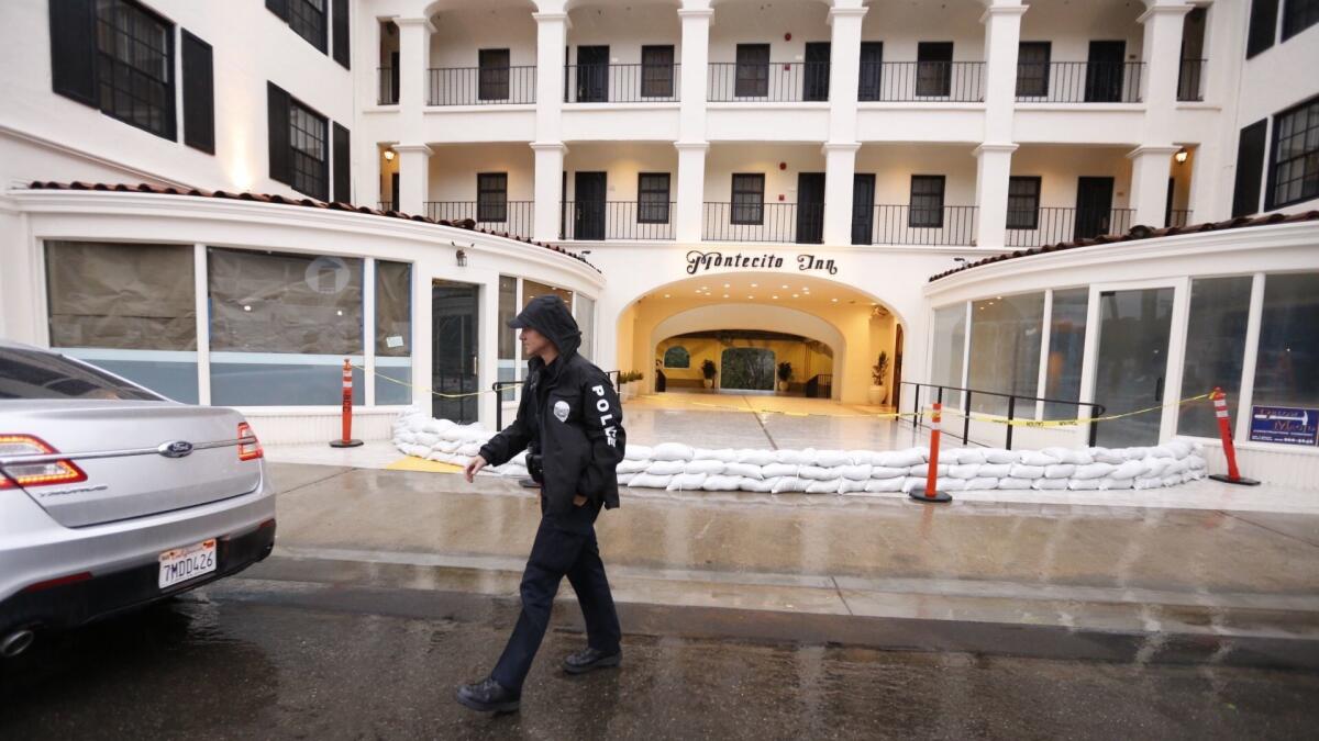 A Santa Barbara police officer on Thursday morning checks on the Montecito Inn, its entrance surrounded by sandbags, as rain falls for the second day in a row in Southern California.