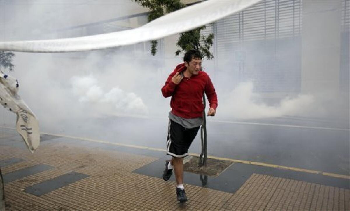A man run away from tear gas, shot by police officers, during looting in Concepcion, Chile, Sunday, Feb. 28, 2010. A 8.8-magnitude earthquake hit Chile early Saturday. (AP Photo/ Natacha Pisarenko)