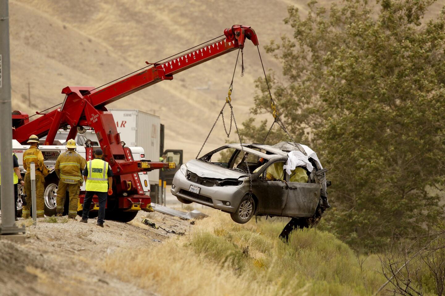 A heavy tow truck lifts a vehicle to the side of the 5 freeway as investigators look over the scene of an accident on Tuesday, June 28, 2016 in Gorman, Calif. A minivan got in a minor collision and stopped on the shoulder. It was still partially in a lane when a semitrailer hit it and it burst into flames with two women and children inside, California Highway Patrol Officer Monica Posada said.