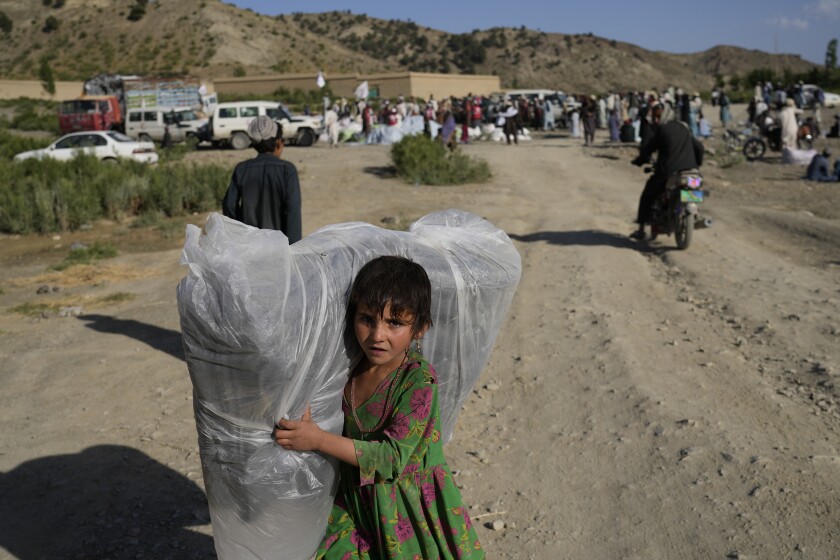 Afghan girl carries a donated matrace after an earthquake in Gayan village, in Paktika province, Afghanistan, Friday, June 24, 2022. A powerful earthquake struck a rugged, mountainous region of eastern Afghanistan early Wednesday, flattening stone and mud-brick homes in the country's deadliest quake in two decades, the state-run news agency reported. (AP Photo/Ebrahim Nooroozi