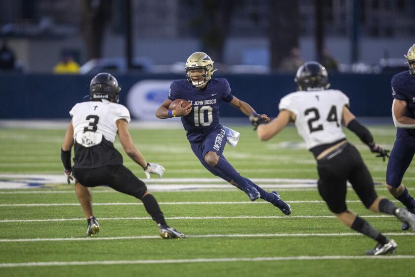 St. John Bosco quarterback Pierce Clarkson scrambles for yardage against Servite on March 26, 2021.