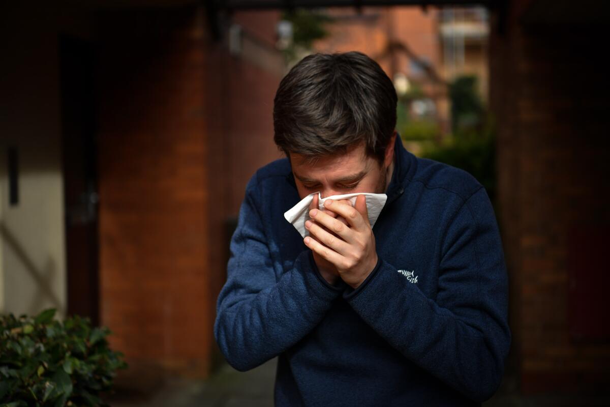 A man sneezes into a tissue