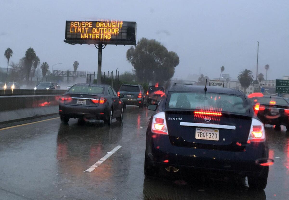 A drought sign along the 101 Freeway reminds people to limit watering during a rainstorm on Tuesday, Sept. 15.