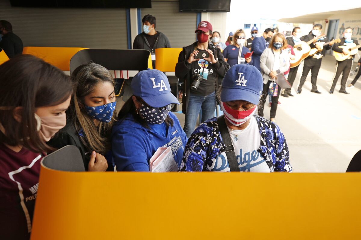 Roxanna Jacinto helps her mother, Salvadora Martir, 73, right, as she votes for the first time at Dodger Stadium.