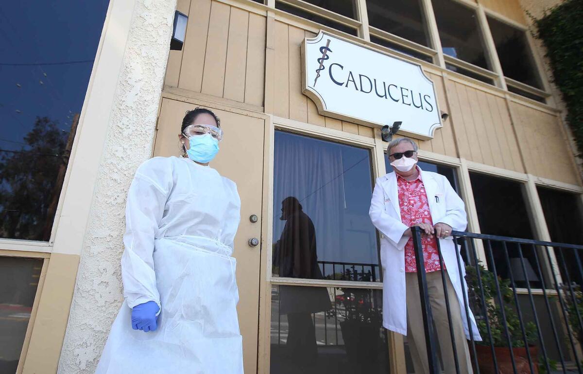 Dr. Gregg DeNicola and assistant Janet Muratalla wait to administer drive-up coronavirus testing outside the Caduceus Medical Group office in Laguna Beach.