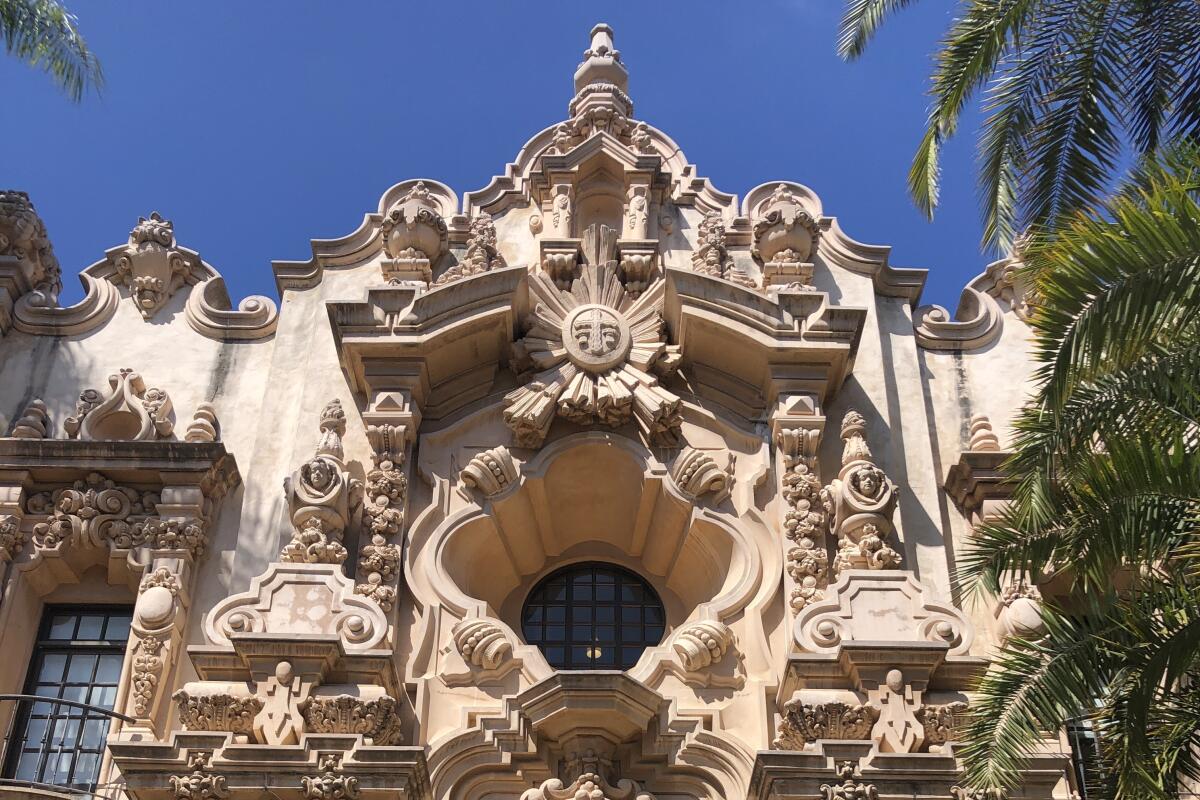 A vertical image shows an arched doorway surrounded by ornate Spanish baroque details and capped by a quatrefoil window