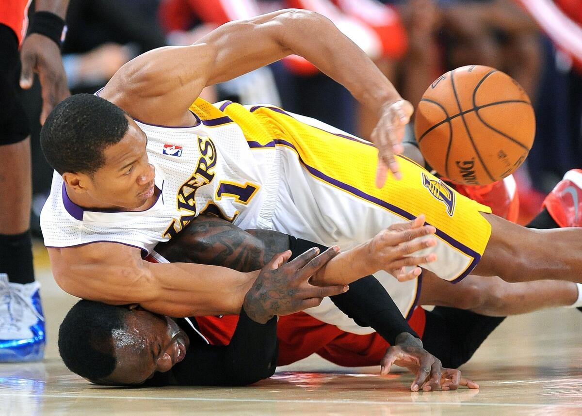 Lakers guard Wesley Johnson, top, battles for a loose ball with Atlanta Hawks guard Dennis Schroder during the first half of Sunday's game at Staples Center.