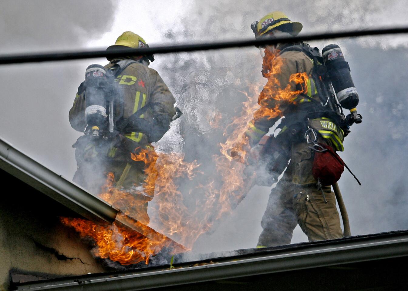 Glendale Fire Dept. firefighters prepare to cut hole in the roof of a burning home on the 1300 block of N. Jackson St. in Glendale on Friday, November 30, 2012.