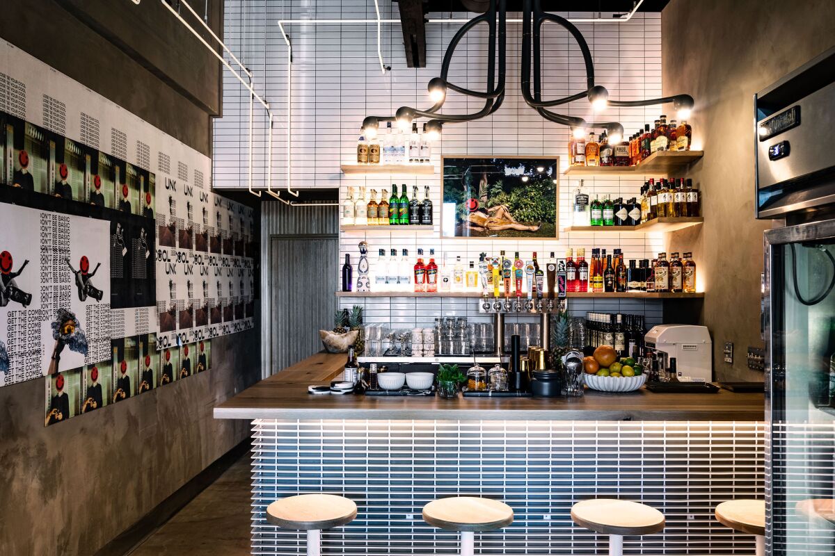 The small interior bar of Uncool features cement walls, modern light fixtures and white and black tile.