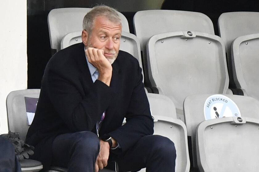 Chelsea soccer club owner Roman Abramovich sits alone in the stands with his hand holding his chin