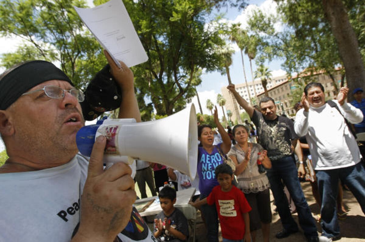 On the grounds of the Arizona state capitol in Phoenix, William Robles waves a copy of an injunction blocking a key provision of Arizona's immigration law in July 2010.