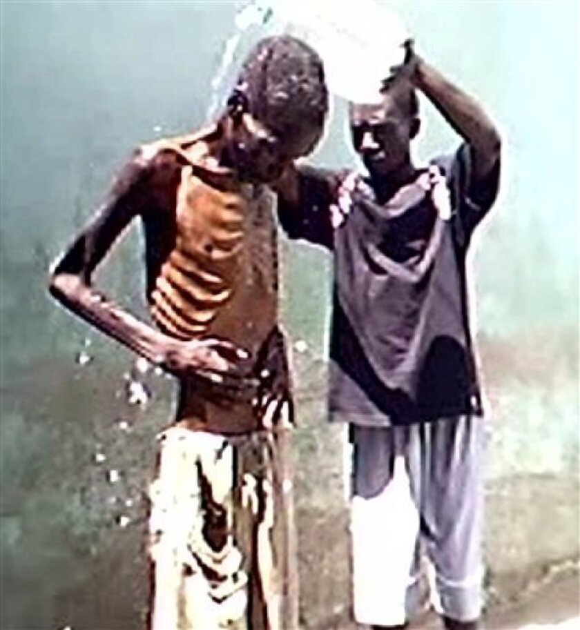 In this image made from video provided by the Special Assignment program titled "Hell Hole" a prisoner helps an inmate wash during undercover filming for the documentary aired Tuesday March 31. 2009. Images from inside Zimbabwe's prison, of inmates so weak from hunger they can't stand, are shocking proof of the impact of the country's economic collapse on those who can't escape, said a producer who helped make the behind-the-walls documentary. (AP Photo/Special Assignment) THE ASSOCIATED PRESS COULD NOT INDEPENDENTLY DETERMINE IF THE PRISONERS' AILMENTS WERE CAUSED BY THE JAIL CONDITIONS OR BY AN ILLNESS OR MALNUTRITION THEY WERE SUFFERING BEFORE BEING INCARCERATED.
