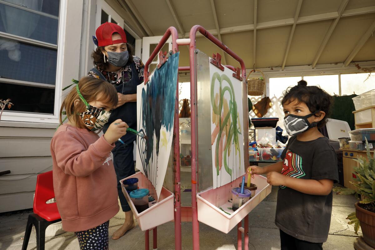 Kirsten Hove, left, works with two children doing watercolor paintings. 