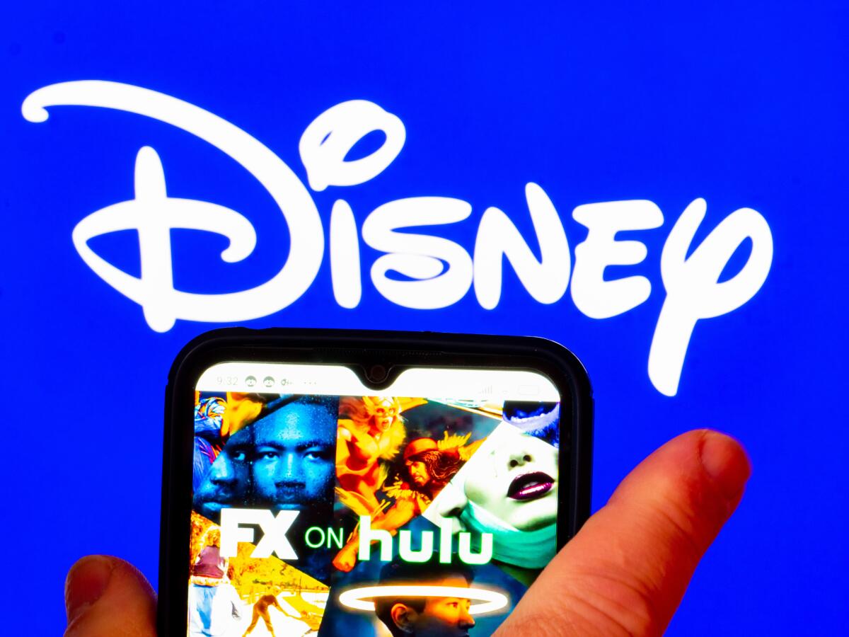 The FX on Hulu logo is displayed on a smartphone screen with a Disney logo in the background.  