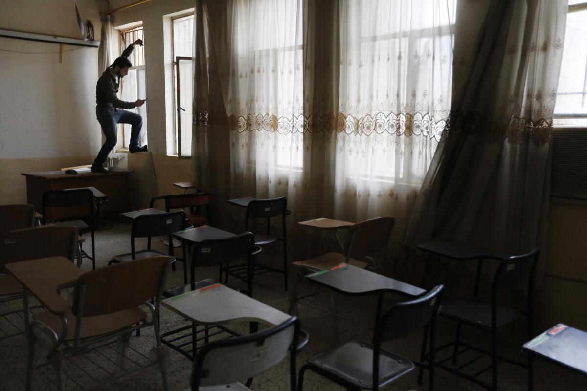 Monther Al-Abasy replaces broken windows at an operational research building on campus. (Marcus Yam / Los Angeles Times)