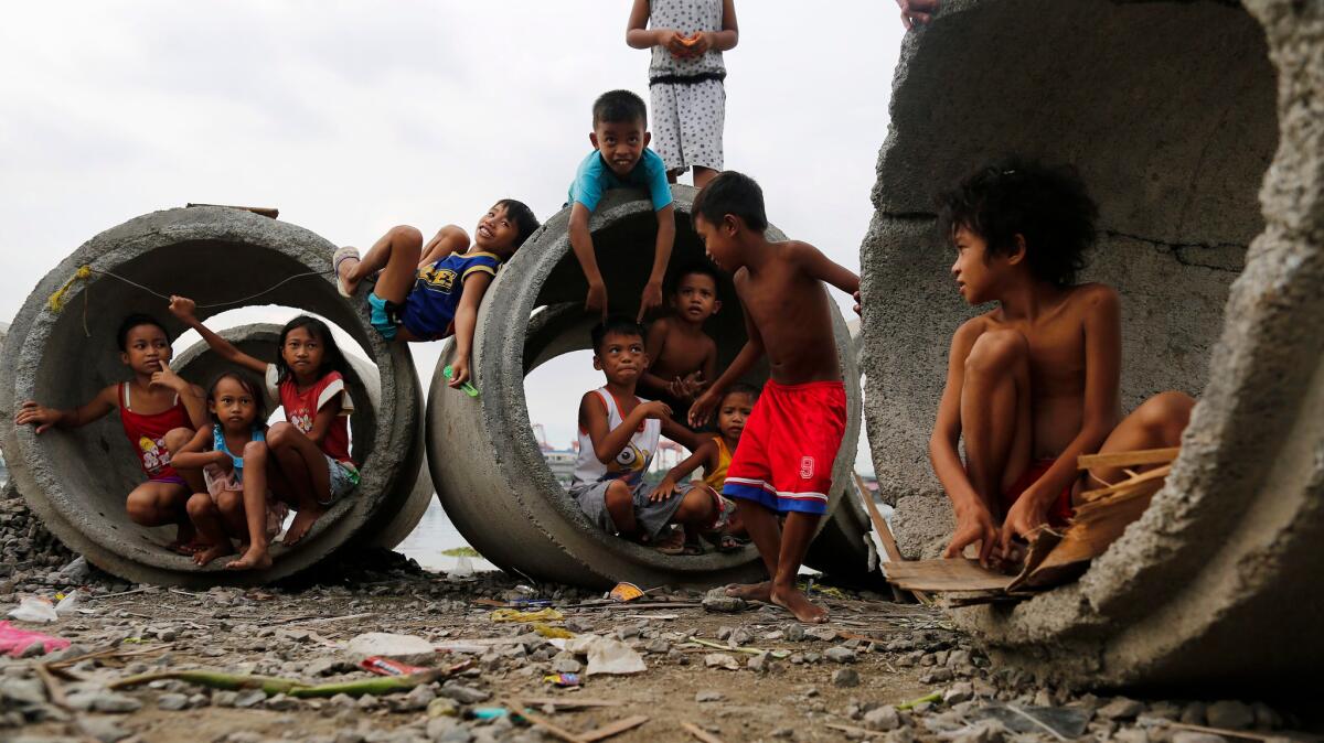 Filipino children rest amongst culverts at a shantytown in Manila, Philippines.