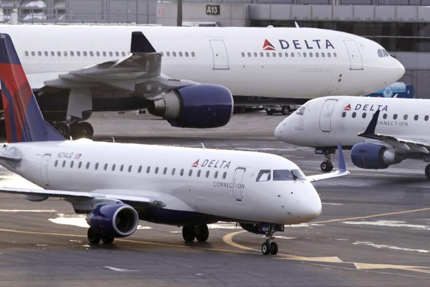 A Delta Connection Embraer 175 aircraft, foreground, taxis to a gate at Logan International Airport in Boston, Monday, Jan. 8, 2018. (AP Photo/Charles Krupa)