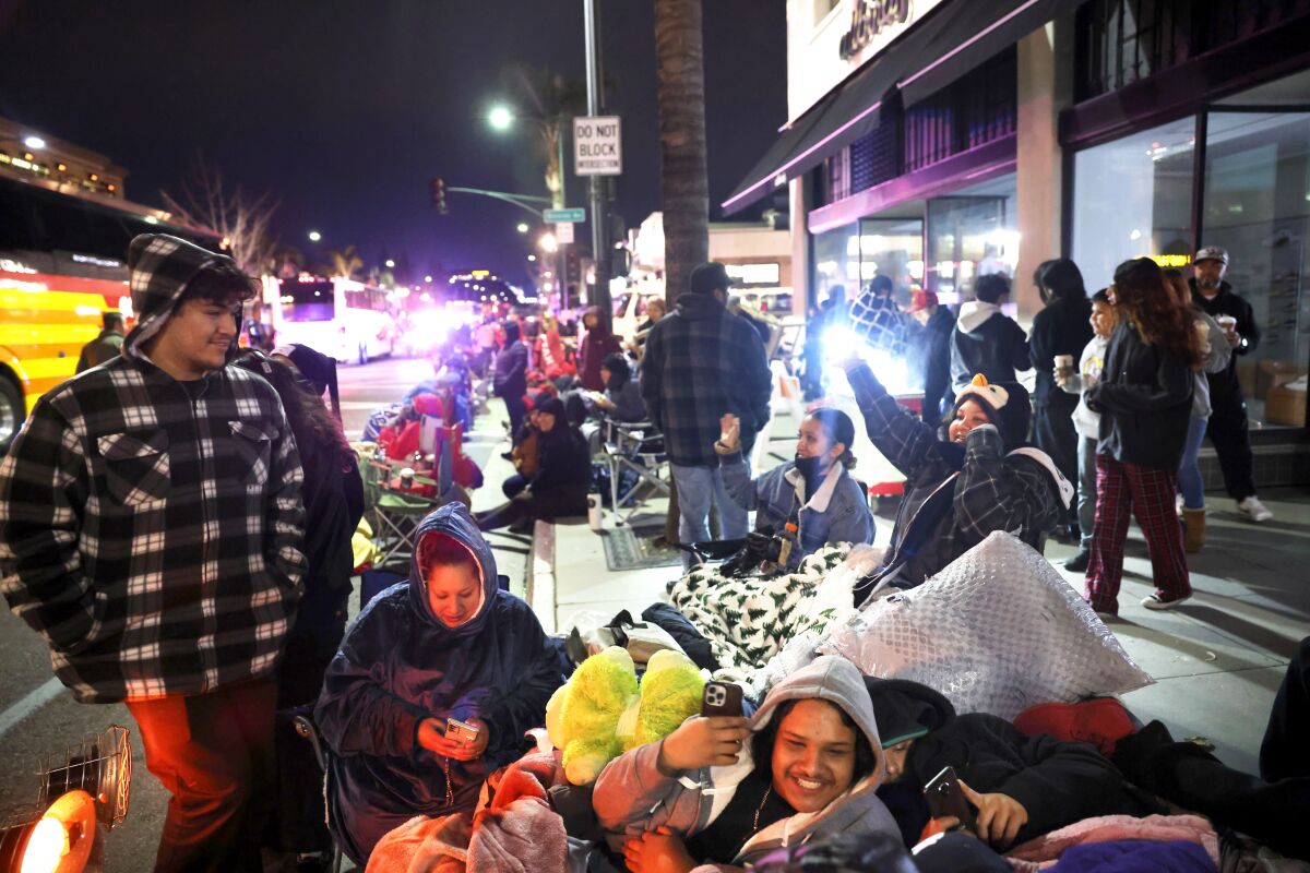 People smile as they wait on Colorado Boulevard.