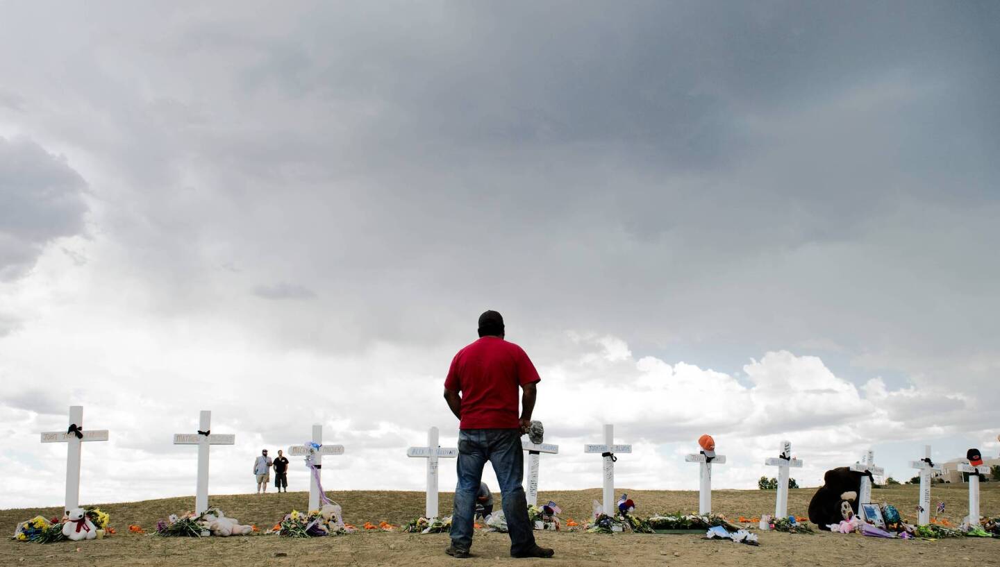A man pauses at the crosses at a memorial near the Century 16 movie theater in Aurora, Colorado. Twelve crosses were erected for the victims who died at the theater mass-shooting.