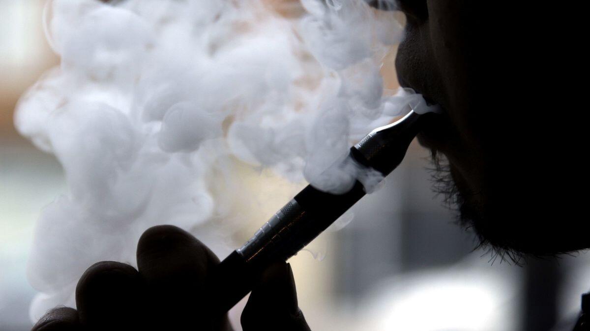 A cloud of smoke surrounds a man vaping. 