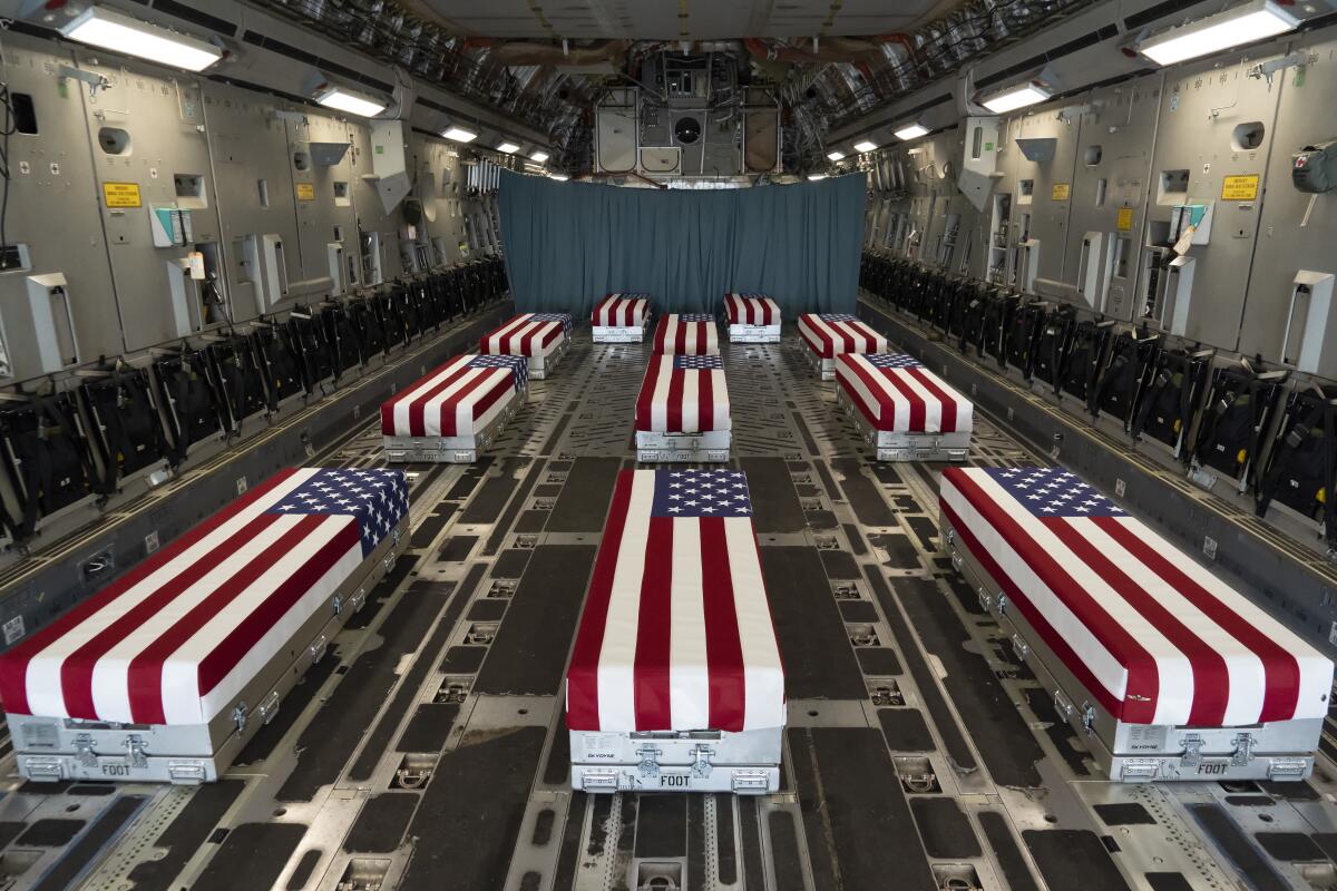 Flag-draped transfer cases carrying the remains of troops killed in Afghanistan line the inside of a transport plane 