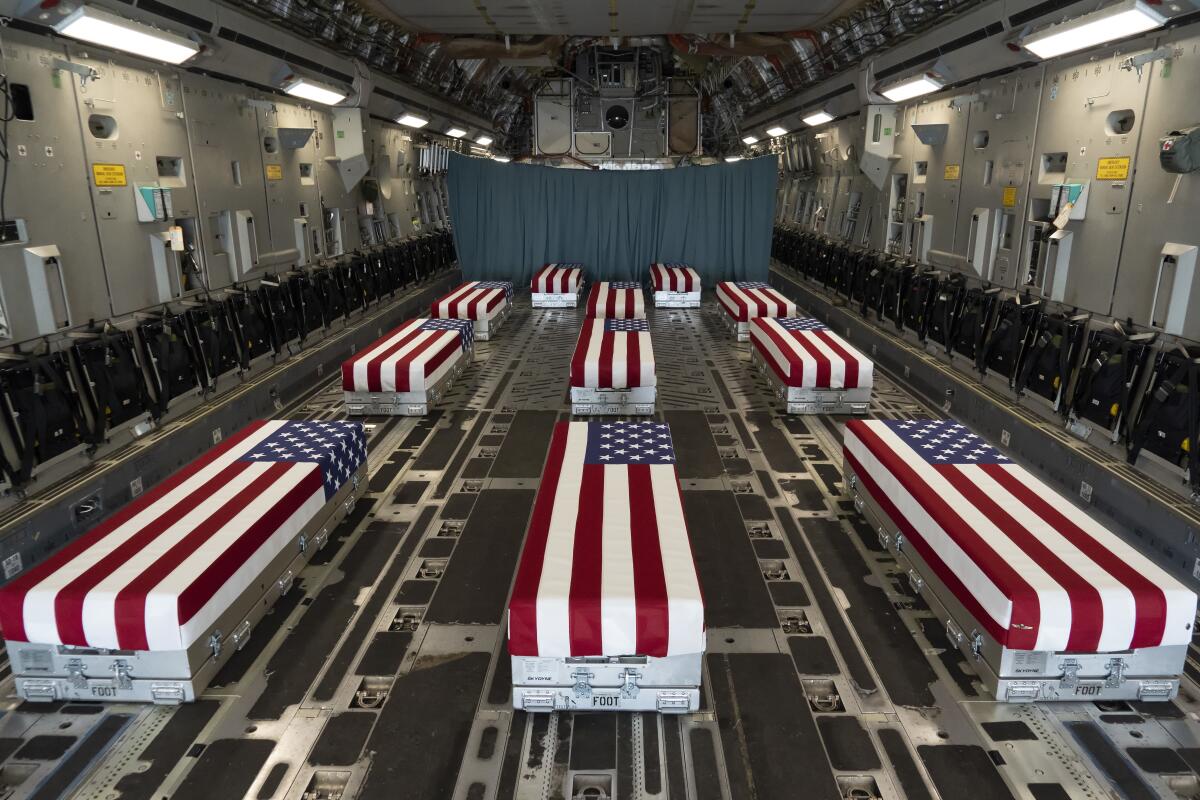 Flag-draped transfer cases carrying the remains of troops killed in Afghanistan line the inside of a transport plane