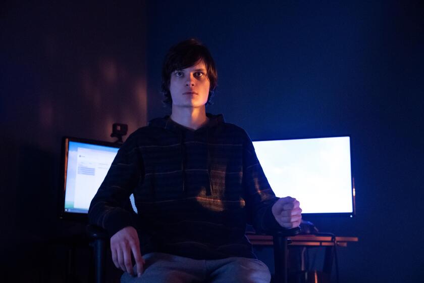 A teenage boy sitting in front of computer screens