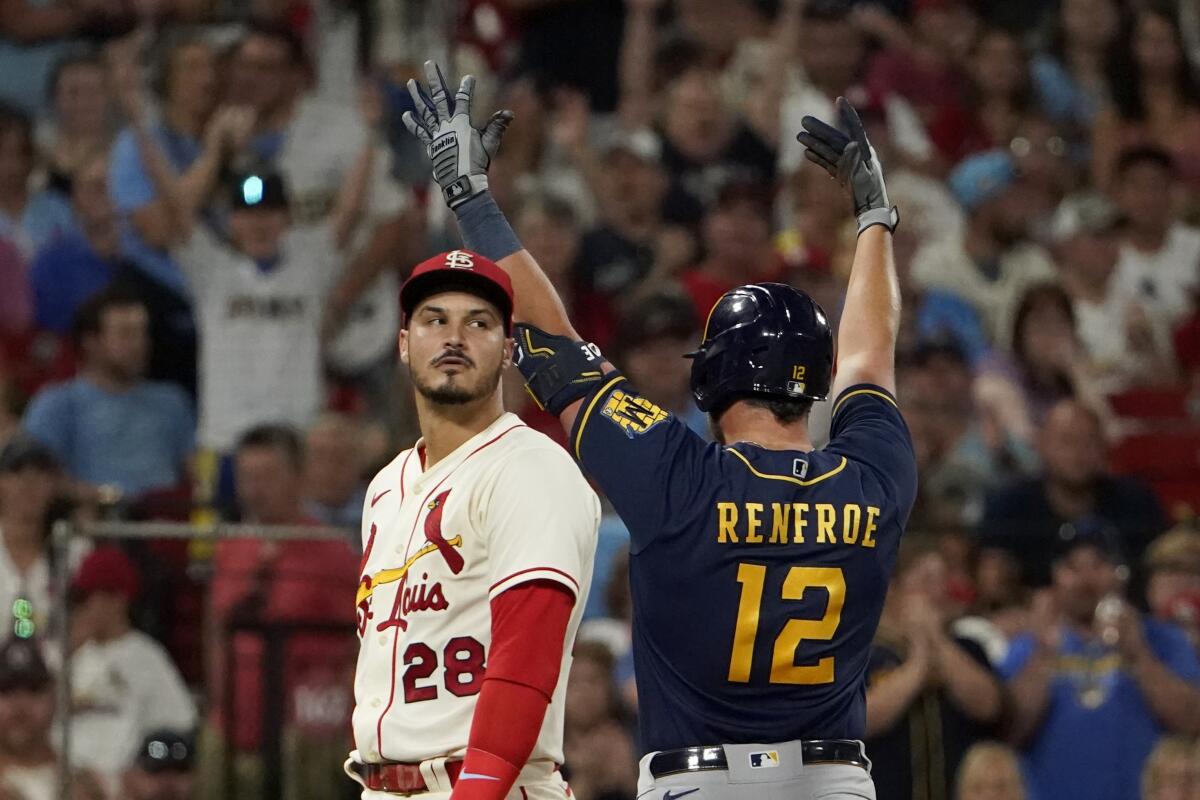 Milwaukee Brewers' Hunter Renfroe (12) celebrates alongside St. Louis Cardinals third baseman Nolan Arenado (28) after hitting an RBI triple during the 10th inning of a baseball game Saturday, Aug. 13, 2022, in St. Louis. (AP Photo/Jeff Roberson)