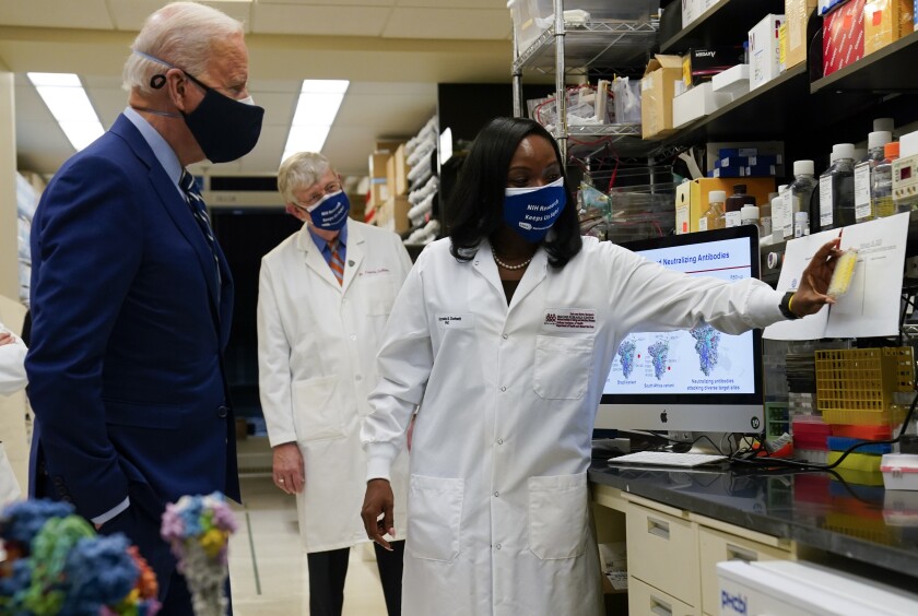 President Joe Biden listens as Kizzmekia Corbett, an immunologist with the Vaccine Research Center at the National Institutes of Health (NIH), right, speaks during a visit at the Viral Pathogenesis Laboratory at the NIH, Thursday, Feb. 11, 2021, in Bethesda, Md. NIH Director Francis Collins is at center. (AP Photo/Evan Vucci)