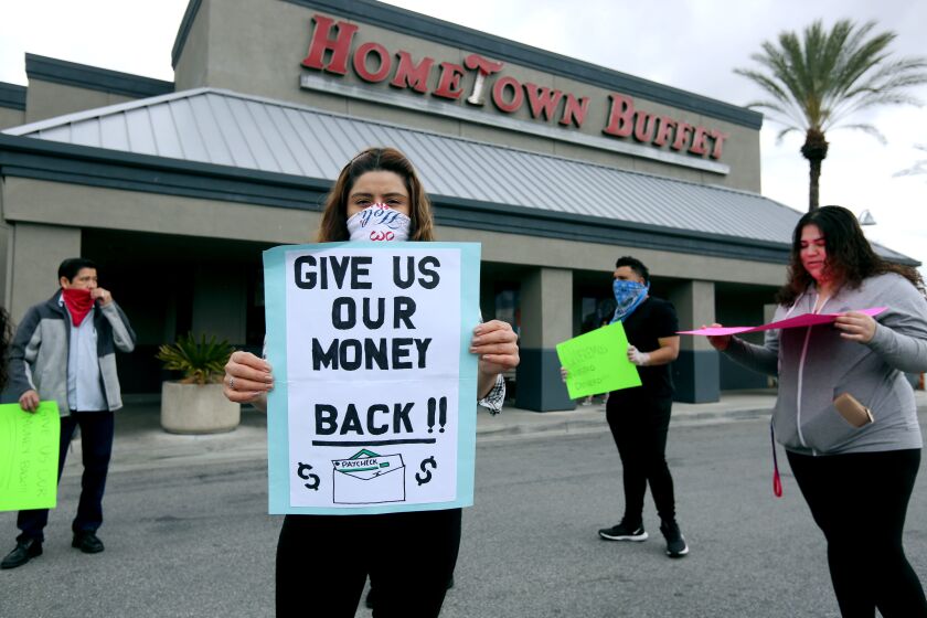 Hometown Buffet waitress Yadira Ugas holds up a sign in front of the now-closed buffet restaurant at the Empire Center in Burbank on Wednesday, April 8, 2020. Employees say the company deposited their mid-March paychecks only to withdraw them one to two days later from their bank accounts. Although Ugas was able to move her money to a second account before this happened, she wanted to show solidarity with her coworkers.