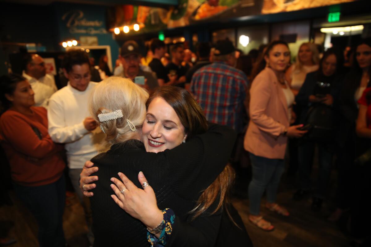 Imelda Padilla gets a hug at a crowded party.