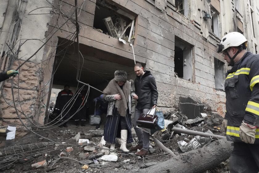 Un hombre ayuda a una mujer a salir de un edificio residencial alcanzado por un cohete ruso en el centro de Járkiv, Ucrania, el domingo 5 de febrero de 2023. (AP Foto/Andrii Marienko)