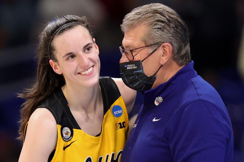 UConn coach Geno Auriemma wears a mask while speaking with Iowa's Caitlin Clark