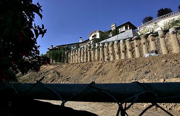 A huge retaining wall stretches along Nimes Road in Bel-Air, one of the Westside communities where wealthy homeowners seeking privacy are buying adjacent properties to create their own residential compounds.