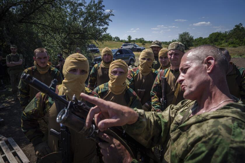 A Ukrainian military instructor of Arey Battalion demonstrates to convict prisoners who have joined the Ukrainian Army how to use a grenade luncher on a rifle during training at the polygon, in the Dnipropetrovsk region, Ukraine, June 22, 2024. Ukraine is expanding its military recruiting to cope with battlefield shortages more than two years into fighting Russia's full-scale invasion. (AP Photo/Evgeniy Maloletka)