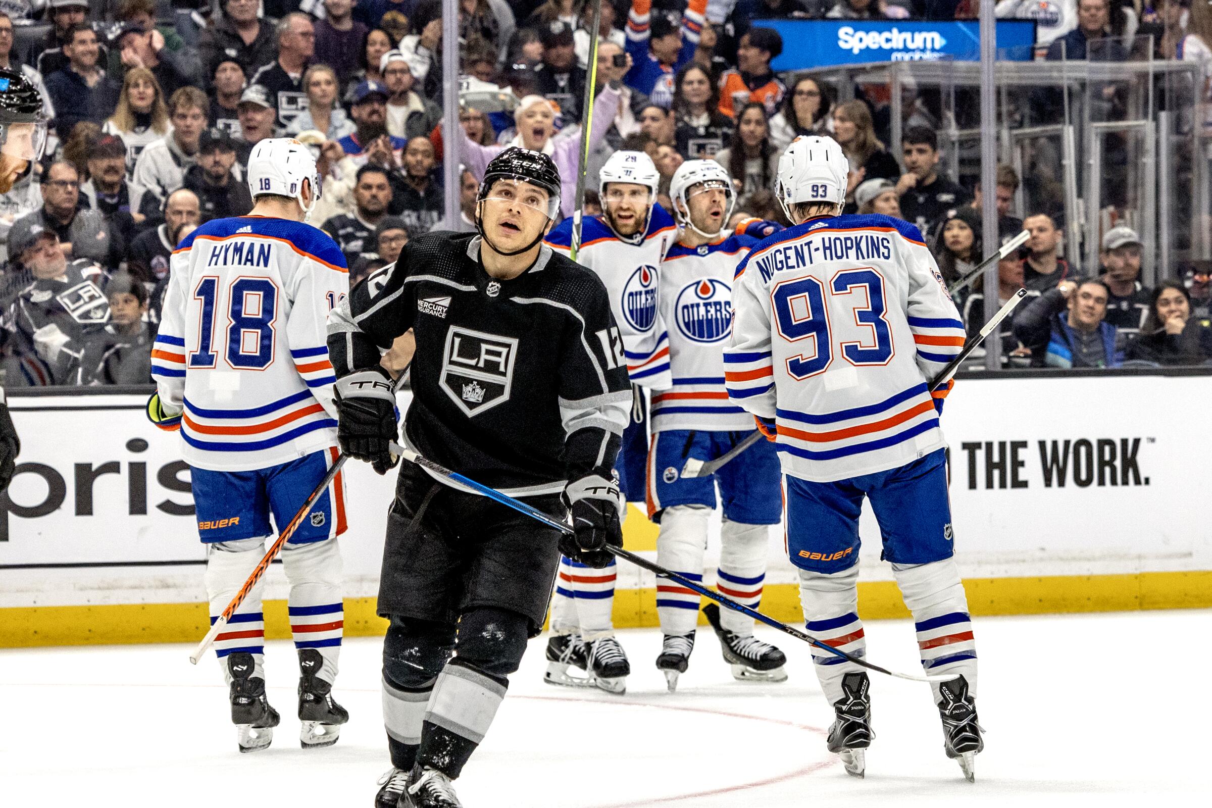 Edmonton Oilers players celebrate a power-play goal by Evan Bouchard as Kings forward Trevor Moore skates away.