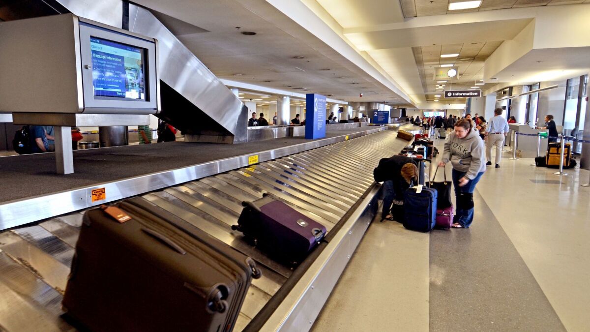 Passengers pick up their luggage at Los Angeles International Airport. The National Economic Council issued a report that criticized "hidden fees" charged by airlines and other businesses.