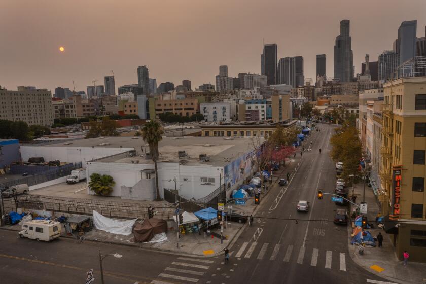 Los Angeles, CA - September 23: An aerial view of homeless encampments in Skid Row as smoke from California wildfires obscures the setting sun and skyline on Thursday, Sept. 23, 2021 in Los Angeles, CA. A federal appeals court on Thursday unanimously overturned a a judge's decision that would have required Los Angeles to offer some form of shelter or housing to the entire homeless population of skid row by October. (Allen J. Schaben / Los Angeles Times)