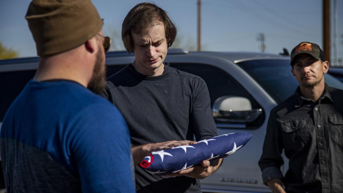 Taylor Hudson, middle, passes to Justin Schnepp the flag draped over the casket of their friend Kevin Howard.